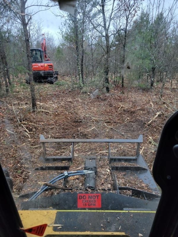 Trail clearing in progress from a skid steer with brush mower attachment and a mini excavator removing trees